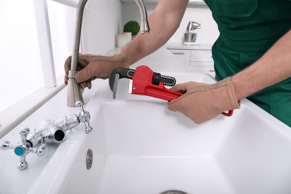 Plumber fixing kitchen faucet